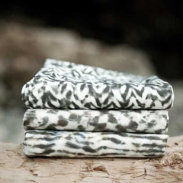 Carley Kahn upholstery fabrics. Three patterns are folded and stacked on log. 