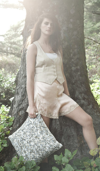 Carley Kahn "Stripe" pillow cover. Model is holding pillow in one hand as it hangs by her side and she rests against tree.