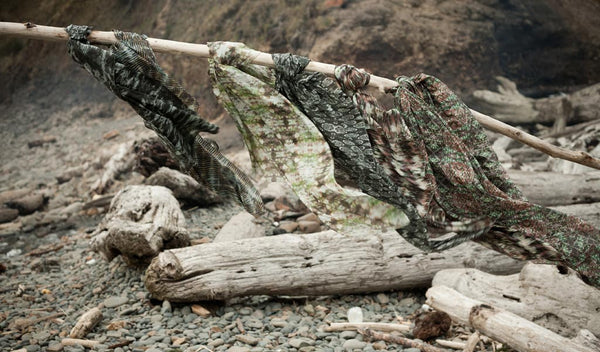 Carley Kahn silk scarves. Six of them blowing in wind while tied to long stick. Driftwood and beach in background. 